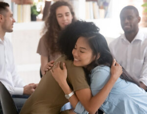 two individuals in a support group hugging