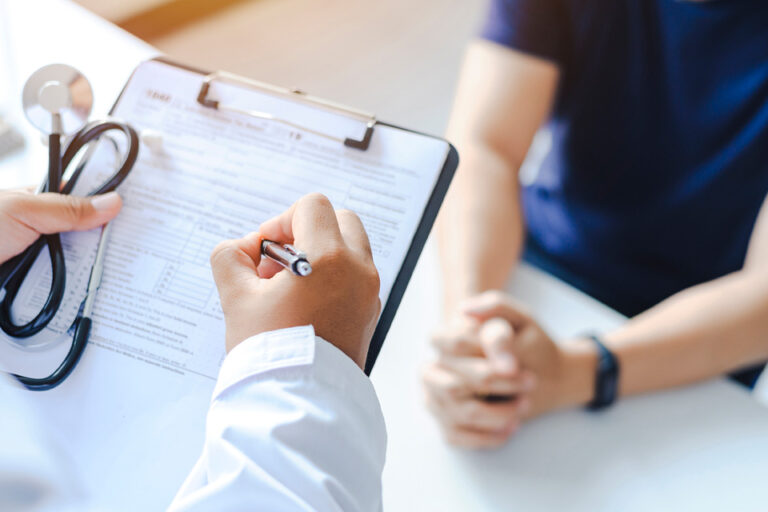 medical professional completing a form for a patient sitting across from them