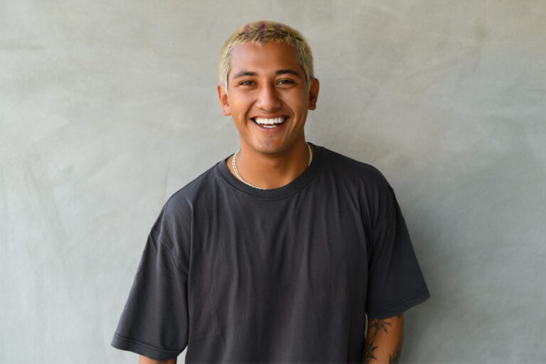 smiling individual in front of a gray background