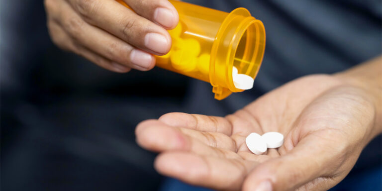 person dispensing pills into their hand