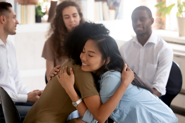 two individuals in a support group hugging