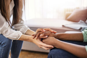 addiction counselor supportively holding the hands of their patient